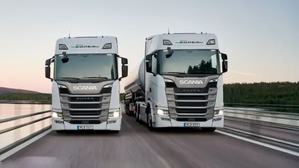 Två nya Scania lastbilar, en med tank, kör på en bro. Kolla in ny Scania lastbil pris för din nästa transport.